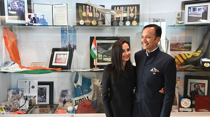  Shallu and Naveen Jindal pose in front of a case containing Naveen’s UTD achievements and memorabilia.